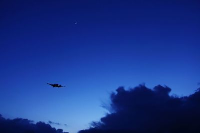 Low angle view of silhouette airplane against clear blue sky