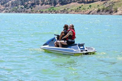 Portrait of smiling woman with mother riding jet boat in sea 