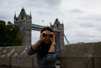 Young woman standing against the sky in city