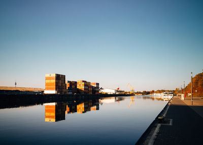 Reflection of buildings in river against clear sky