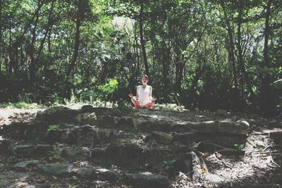 Man sitting on rock in forest