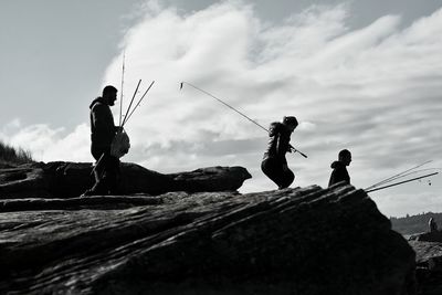 Low angle view of silhouette boy on mountain against cloudy sky