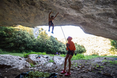 Man with friend balancing on rope in cave