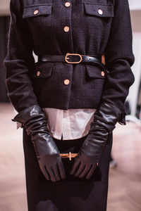 Fashion details of a classy black skirt, leather gloves and classic velvet clutch