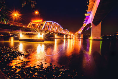 Illuminated bridge over river at night