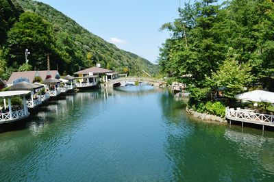 Scenic view of canal by houses and trees against sky