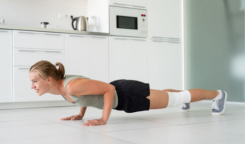 Fitness, home and diet concept. smiling young woman working out at home, in the kitchen