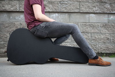 Low section of woman sitting on wall