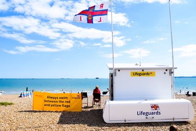 Information sign on beach against sky