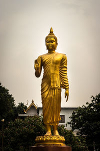 Low angle view of statue against temple building against sky