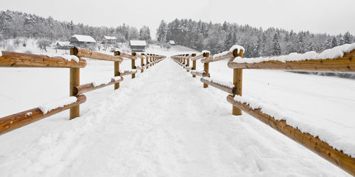 Pathway amidst railing on snow covered field