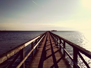 Pier over sea against sky during sunset