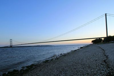 Humber bridge over river against clear sky during sunset