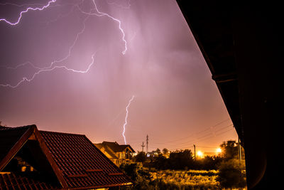 Low angle view of lightning over buildings at night