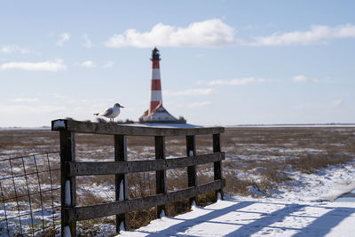 Lighthouse by sea against sky