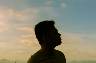 Silhouette young man looking away standing against sky during sunset