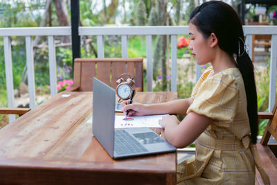 Side view of woman using mobile phone on table