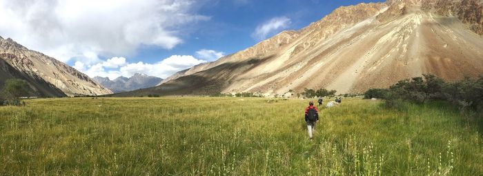 Woman walking on field against mountain range