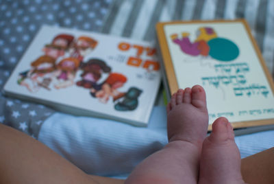 Close-up of baby feet with books on bed