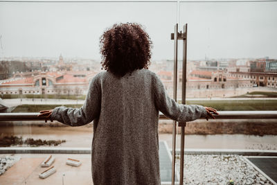 Rear view of woman standing against railing in city