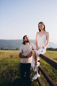 Young couple standing on land against clear sky