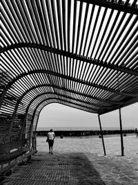 Woman walking by sea against sky