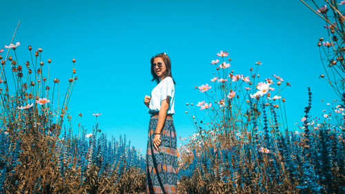 Young woman standing on field against sky