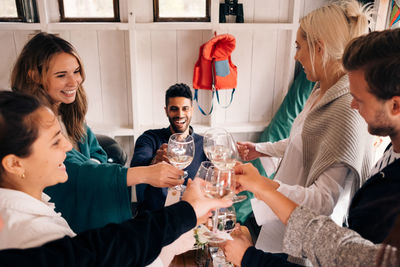 High angle view of happy young friends toasting wineglasses during lunch party