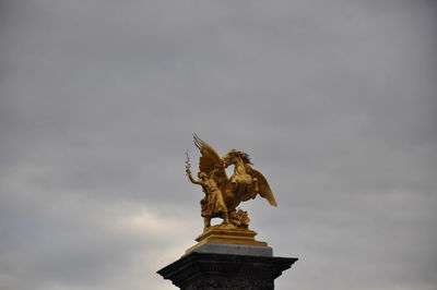 Low angle view of golden statue against sky