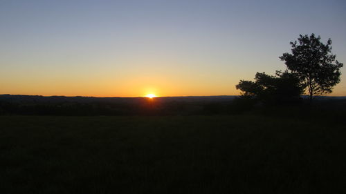 Scenic view of silhouette field against clear sky at sunset