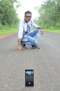 Portrait of young man sitting on road