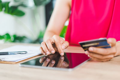 Midsection of woman using mobile phone on table