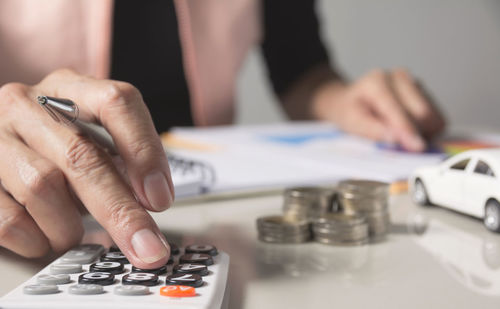 Midsection of man using calculator at office