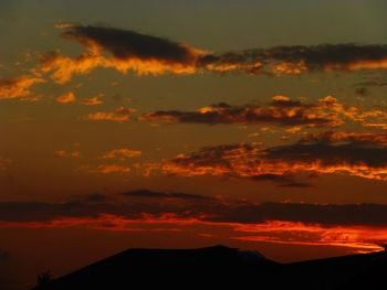 Low angle view of silhouette mountains against romantic sky