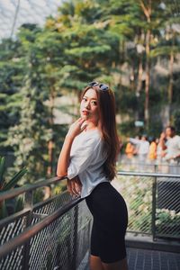 Portrait of woman standing against railing