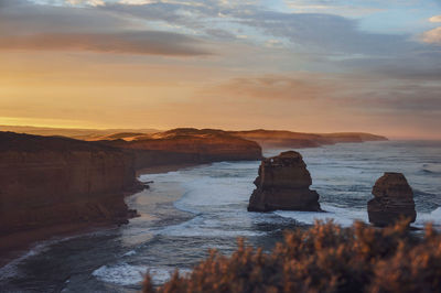 Rocks on sea against sky during sunset