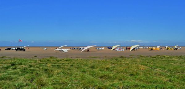 Multiple light aircraft on a beach against blue sky