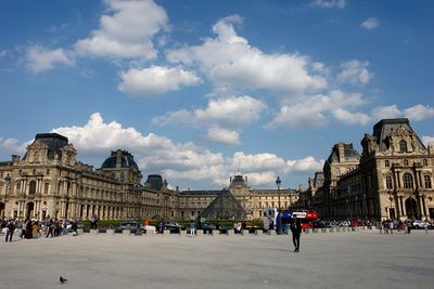 People at town square against cloudy sky