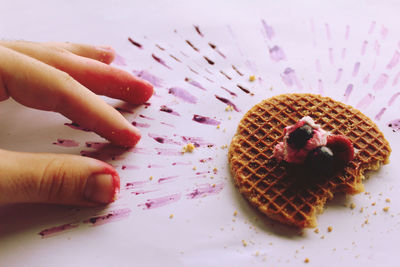 Cropped hand of woman reaching for dessert on table