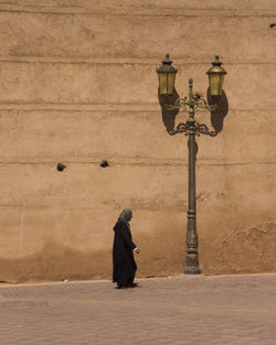 Side view of man on street light against wall