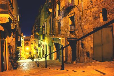 Stairway amidst illuminated buildings against clear sky