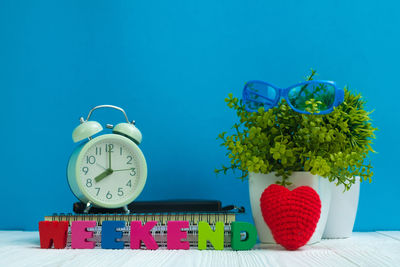 Close-up of clock on table against blue wall
