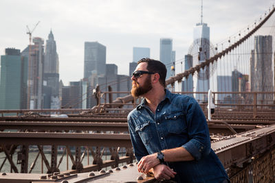 Man standing on bridge against sky in city