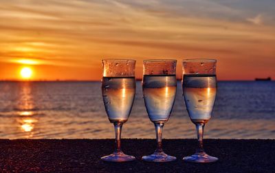 Glass of wine against sea at sunset