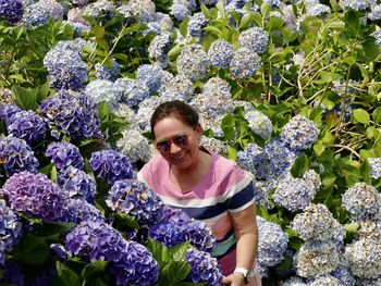 Portrait of a smiling young woman standing on purple flowering plants