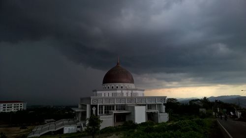 Buildings in city against cloudy sky