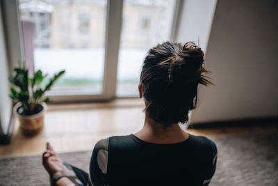 Rear view of woman sitting at home