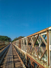 Footbridge over railroad tracks against clear blue sky