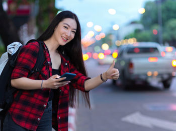 Young woman using phone while standing in city