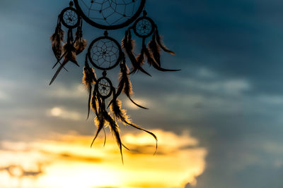 Low angle view of feather against sky during sunset